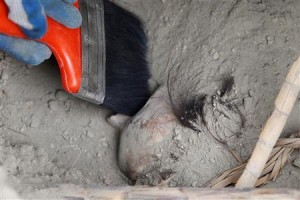 A worker brushes a mummy's skull at a coastal pyramid site called El Castillo de Huarmey